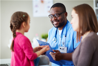 Doctor speaking with little girl with mom in background