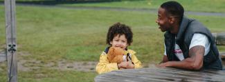 Son and father sitting at a picnic table in the park